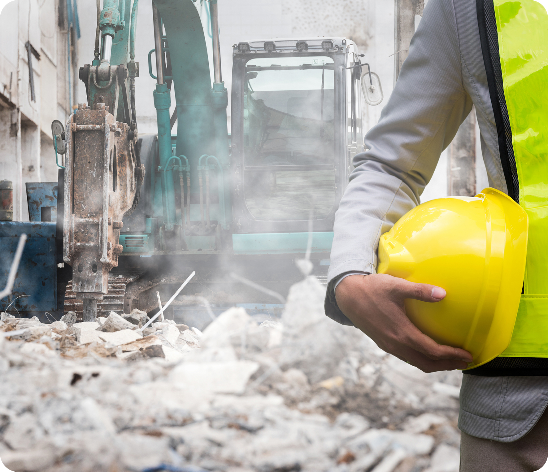 Construction worker holding helmet near excavator.