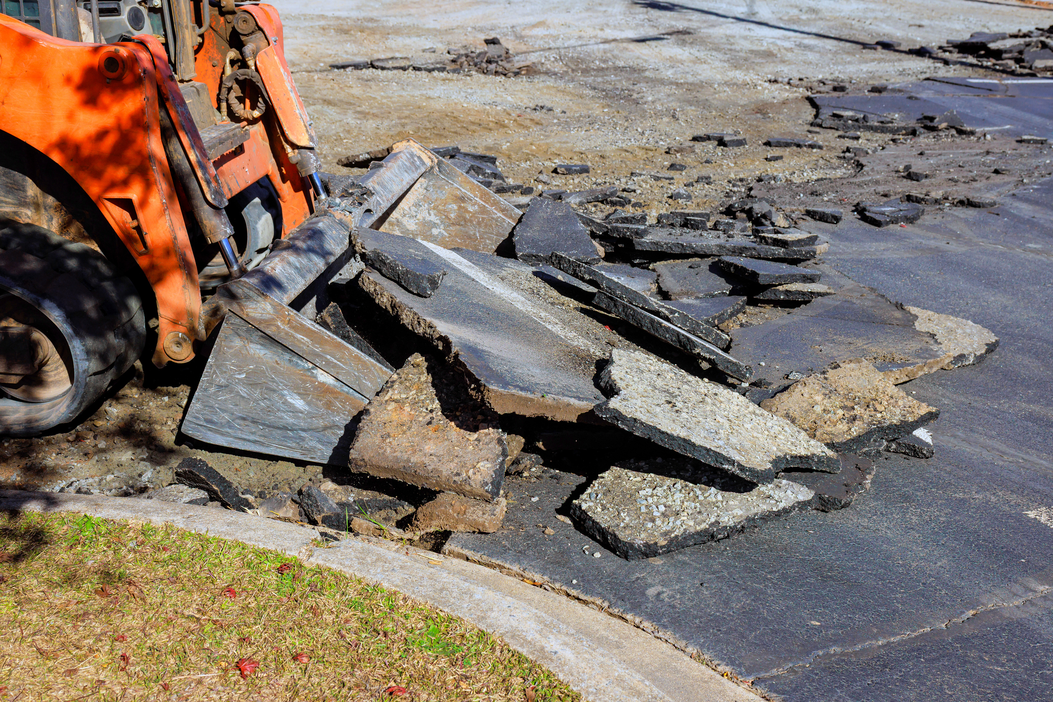Bulldozer breaking asphalt on a street.