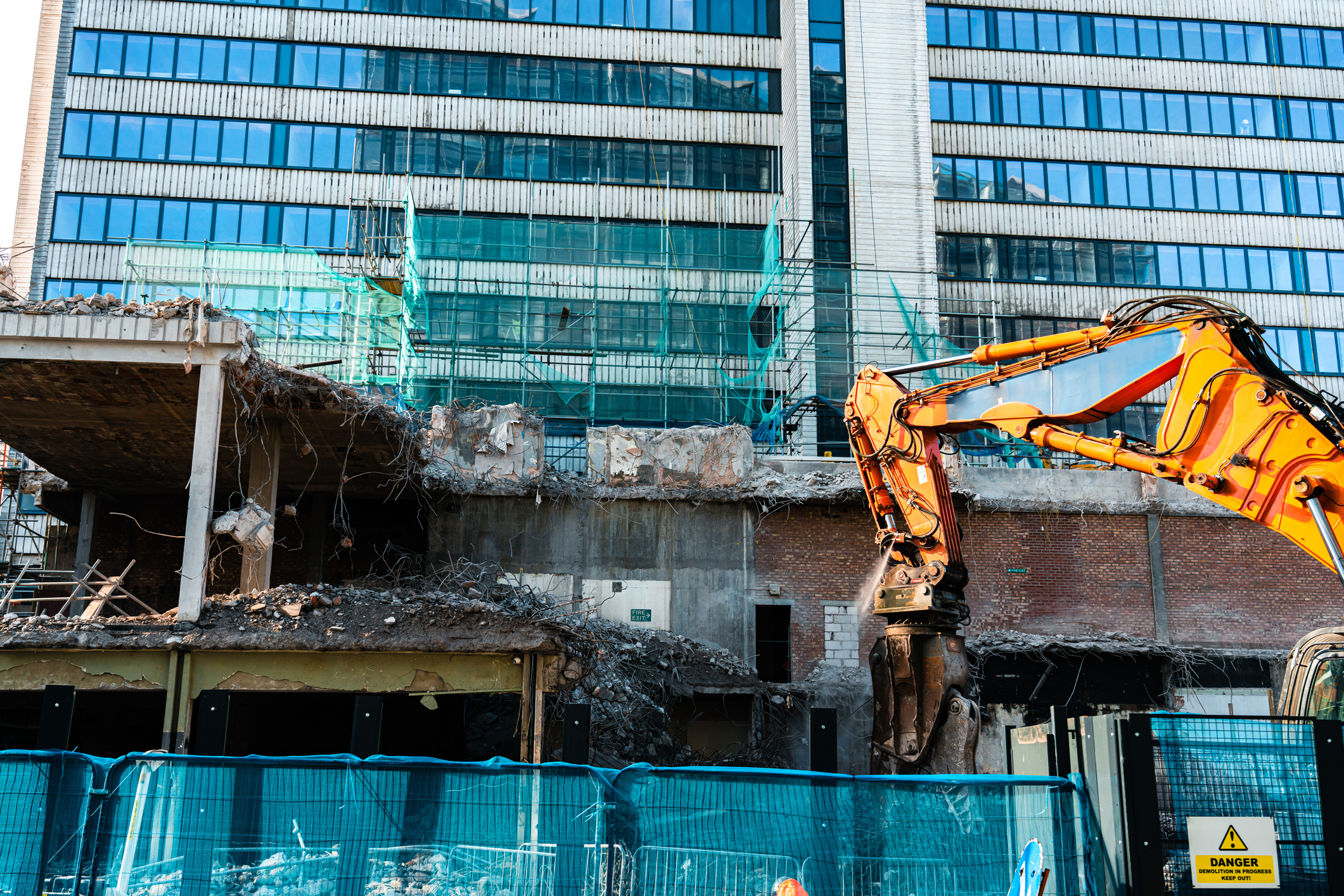 Building demolition with excavator in progress.