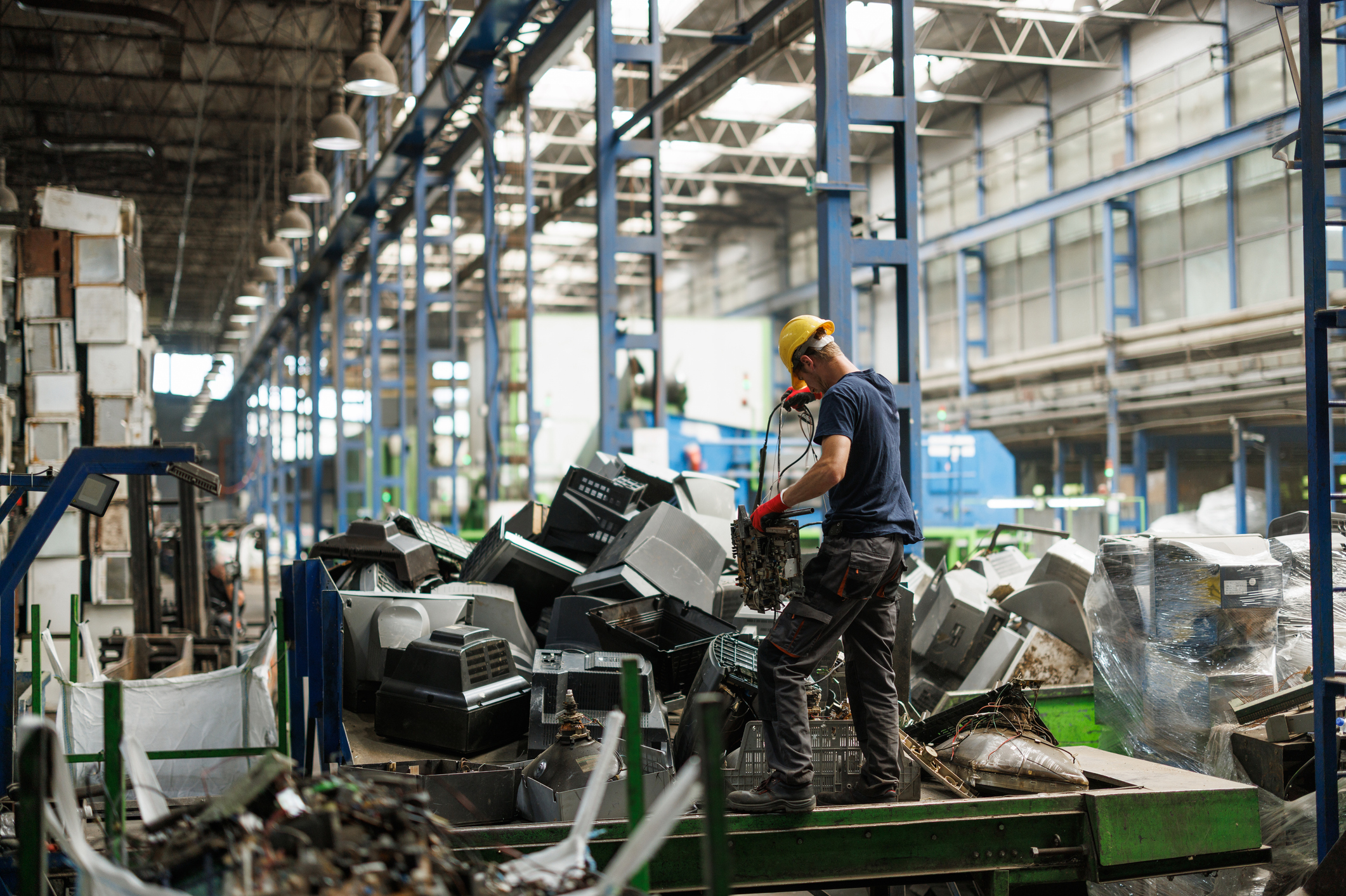 Worker sorting electronics in recycling facility.