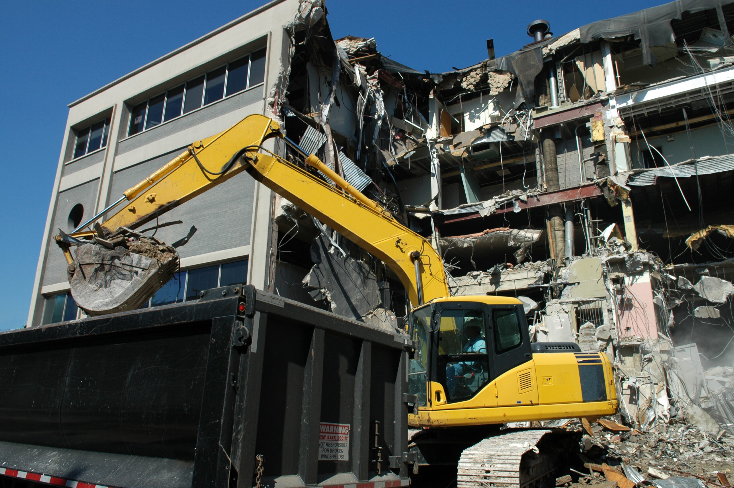 Excavator demolishing a multi-story building.