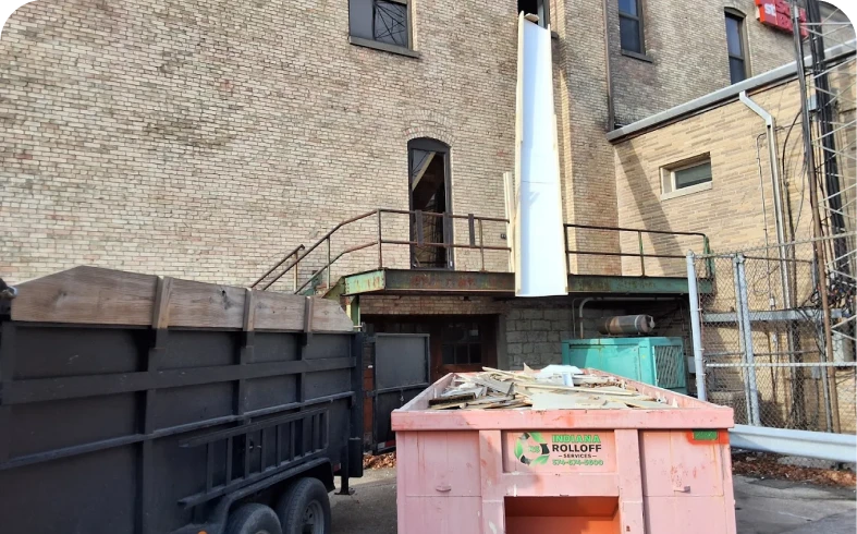 Building with debris chute and dumpsters outside.
