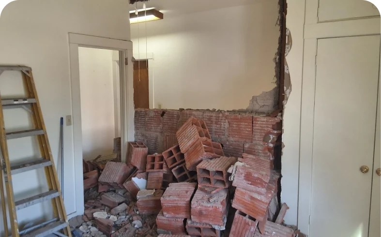 Collapsed brick wall in an unfinished room.