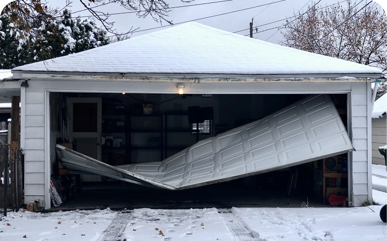 Broken garage door with snow outside.