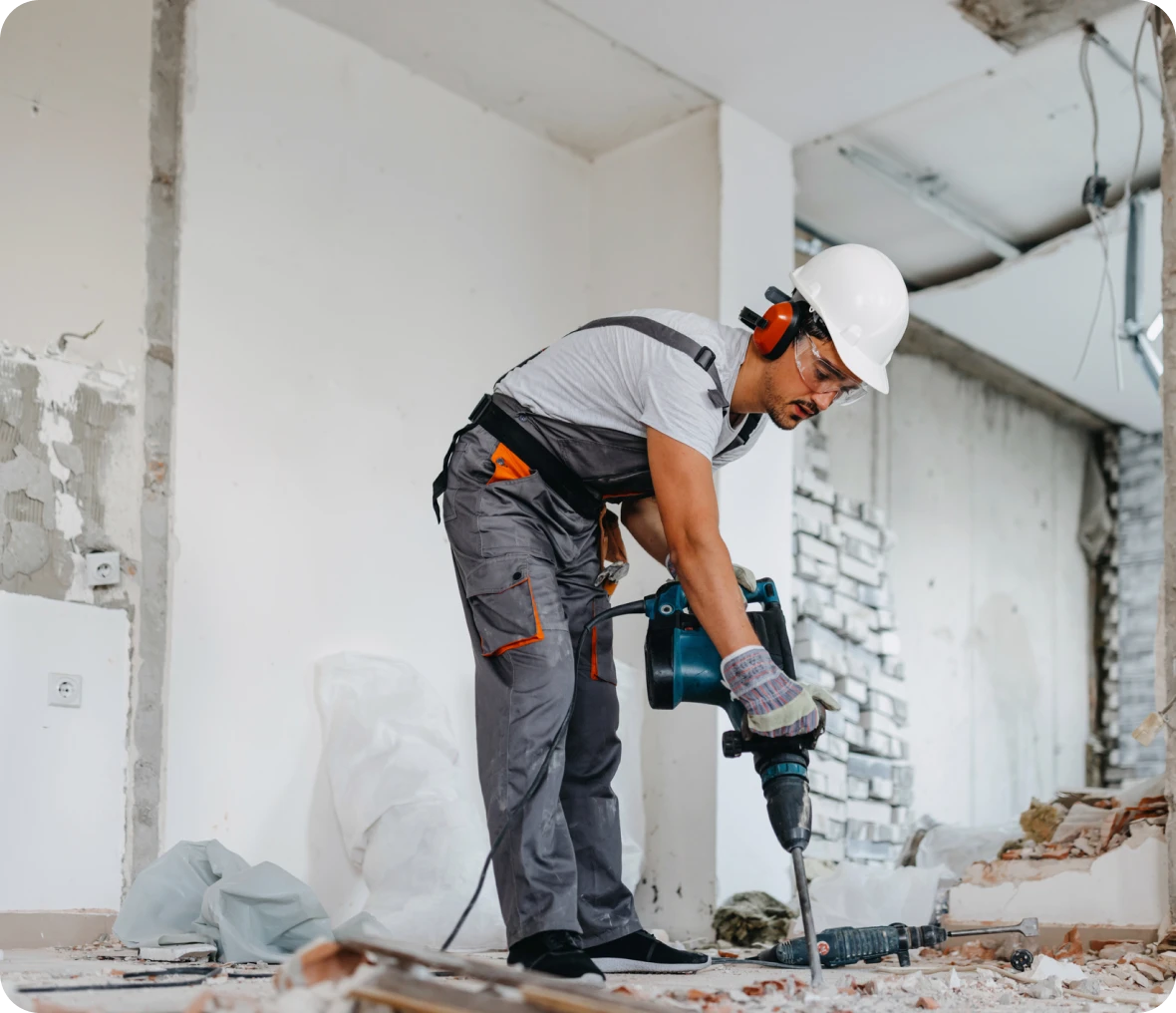 Construction worker using a power drill indoors.