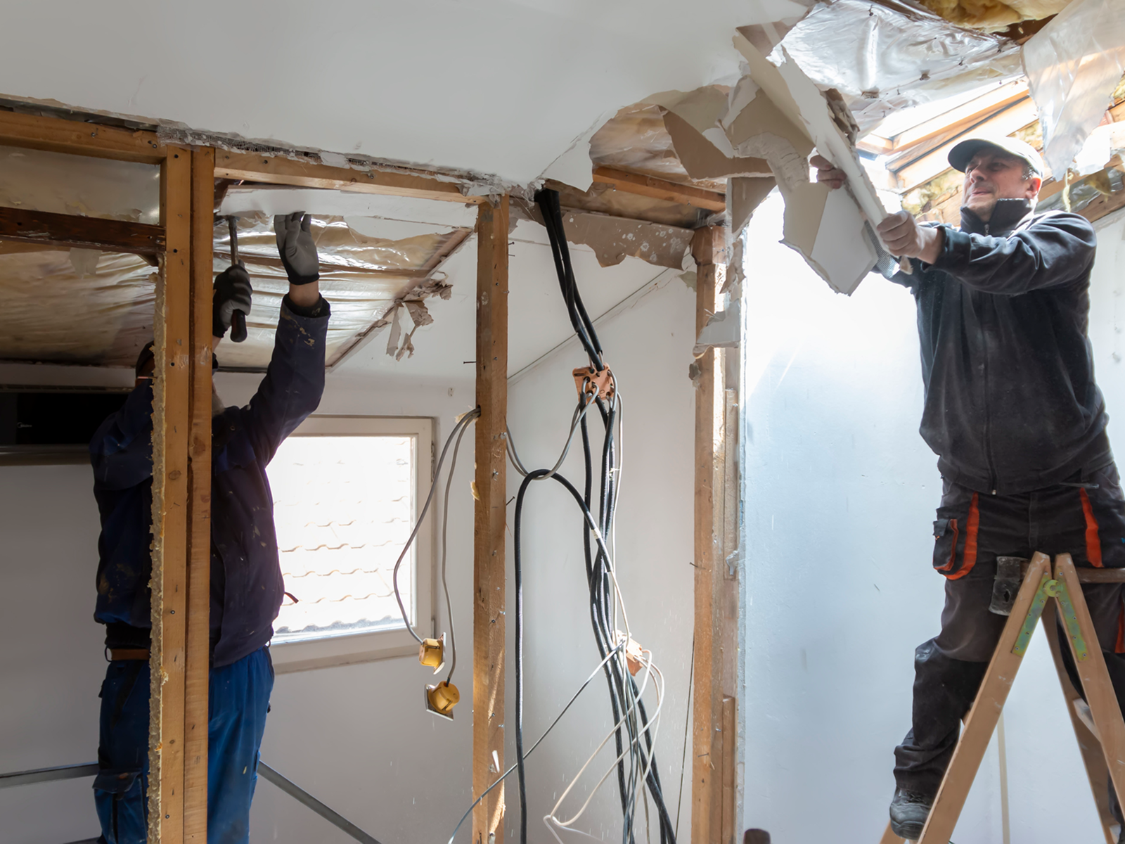 Workers demolishing wall in under-construction room.