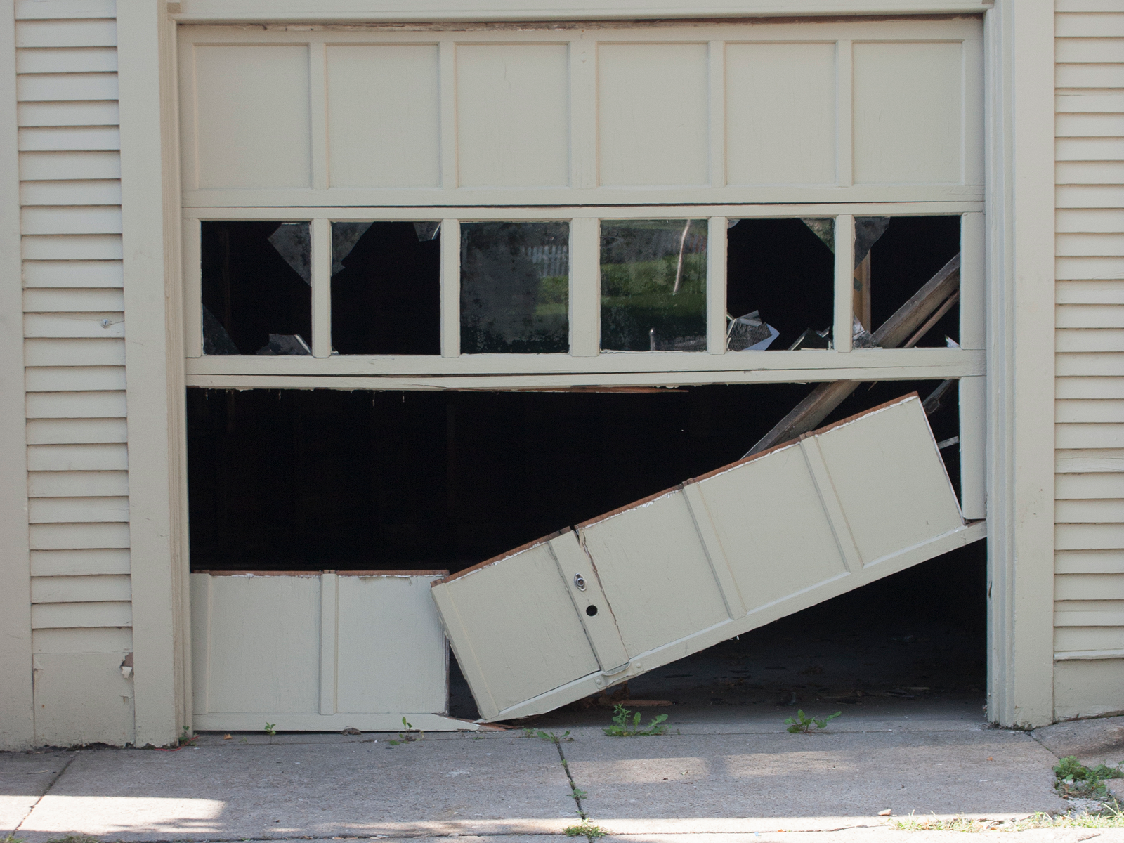 Broken garage door with damaged panels.